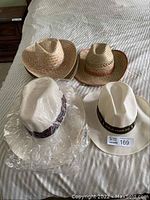 Four cowboy hats shown on bed: two white woven hats including one Sea Horse branded, two natural straw-colored hats