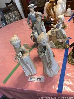 Two porcelain angels holding flowers with signs of minor damage or wear