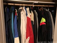 Twenty-eight jackets hung side by side on a closet rod