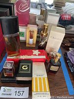 Photo shows multiple perfume bottles including Obsession, Giorgio Close Encounters, and Givaudan with mostly original boxes displayed on a table.