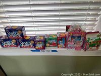 Collection of 7 McDonalds collectible toys including Dalmatian and Barbie-themed boxed items placed on windowsill