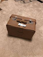 Closed brown leather carrying case with strap and metal locks for vintage Piedmont sewing machine