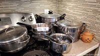 Overview of all pots, pans, garlic roaster on stovetop and counter