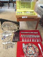 Full view of silverware, tray, glass holder stand, and dessert set with knives on carpet