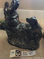 Photo showing the soapstone carving from one side, highlighting the human figure standing and the bear sitting on its hind legs.