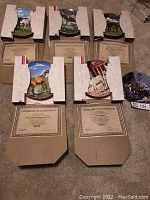 Multiple Spode collector plates in cardboard holders with certificates of authenticity laid out on floor.