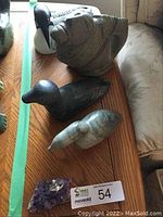 Overview of four bird carvings and amethyst cluster on table