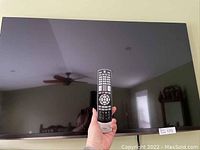 55" Toshiba TV mounted on wall with remote held in front of screen