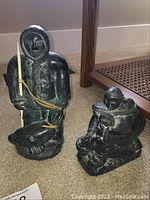 Two soapstone carvings displayed side by side on carpet, full view of both.