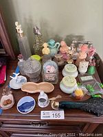 Lot of vintage Avon decanters and assorted decorative pieces arranged on wood surface, showing variety of items.