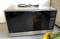 Front view of Panasonic microwave in stainless steel and black glass with digital control panel.