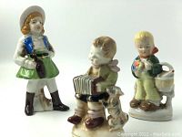 Photo showing three vintage hand-painted porcelain figurines in Renaissance style, including details of their attire and colors.