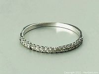 Well-lit close-up showing flat profile of thin sterling silver ring with small stones set along the top half.