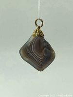 Diamond-shaped agate pendant showing banding pattern and gold-tone bail with decorative cap
