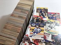 Large stacked collection of hockey cards and several loose cards spread near the stack showing different players and teams.