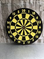 Front side of dartboard showing traditional numbered dartboard with yellow and black segments and numbers 1 through 20