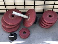 Nine red Healthways weight plates stacked in two groups with a dumbbell handle and collars on ground, showing set composition and physical condition