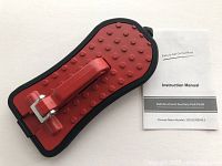 Red foldable auxiliary foot pedal with metal latch, textured surface, and included instruction manual.