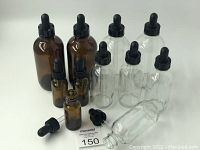 Photo showing 10 glass dropper bottles in two colors amber and clear, with black rubber droppers.