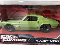 Front side view of the green 1973 Chevy Camaro diecast car model inside the black and red Fast & Furious branded box.