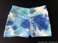 Front view showing blue, teal, and white tie-dye textured women's sport shorts, size medium