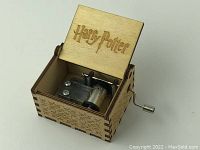 Open wooden music box showing music mechanism and 'Harry Potter' engraved on lid interior.