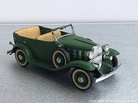Front-side view of green 1932 Chevy sedan diecast model showing chrome grille, headlights, tires, and beige interior seating
