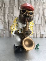 Front view of the large figurine showing man playing tuba with green toy soldier for scale.