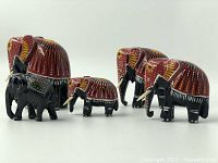 Frontal view of all five wooden elephant figurines showing size variation and colorful painted patterns