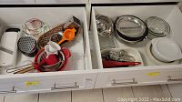 Photo of two open drawers with assorted baking and kitchen supplies including bowls, graters, and utensils.