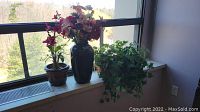 Three faux plants placed on a windowsill showing overall arrangement and scale.