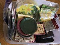 Top-down view of assorted paper plates, napkins, and doilies stacked inside a black storage bin