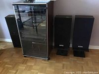 Photo showing the stereo cabinet with four speakers standing beside it: two on speaker stands and two floor-model speakers.