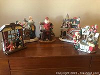 Wide shot showing all five Christmas-themed figurines lined up on a wooden surface against a beige wall.