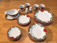 Various plates, bowls, mugs, salt and pepper shakers, and gravy boat displayed on table showing Christmas sunflower pattern and condition.