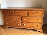 Front view of wooden dresser with six drawers, showing wood grain and distressed finish