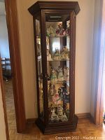 Full view of curio cabinet filled with decorative porcelain figurines to show typical use and interior shelving setup.