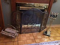 Photo showing the three fireplace accessories including fire screen, log holder with faux logs and fireplace tool set