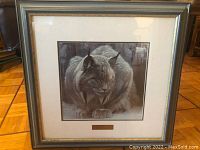 Full view of framed artwork showing the lynx in muted, natural colors with a metallic frame and mounted name plate.