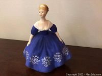 Front view of the Royal Doulton 'Nina' porcelain figurine showing the figure in a blue dress with white floral detail.