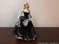 Front view of Royal Doulton 'Special Wishes' figurine showing the woman in a black strapless gown holding a silver shawl with her right hand down and left hand near her chest.