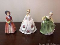 Front view of three Royal Doulton figurines showing detailed dresses and poses