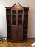 Full frontal view of the secretary desk showing the upper hutch with glass cabinets and side shelves, middle drawer section, and lower cabinet doors.