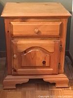 Front view of one wooden side table showing drawer, cabinet door, and distressed surface with scratches and dents.