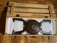 Top-down view of the wooden carrying case opened to reveal the wooden discus and horseshoes inside, foam padding visible.
