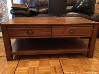Front view of rectangular coffee table showing two drawers and lower shelf