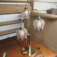 Photo showing the entire decorative glass flower desk lamp with three pink frosted glass shades and brass tone metal base, sitting on a wooden table.