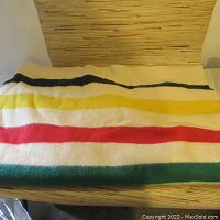 Full view of wool blanket on wooden bench showing horizontal stripes and overall condition