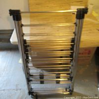 Full view of folded metal laundry drying rack with multiple rods and black plastic connectors.