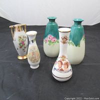 Five decorative vintage vases of varying styles and sizes, shown together on a black cloth background